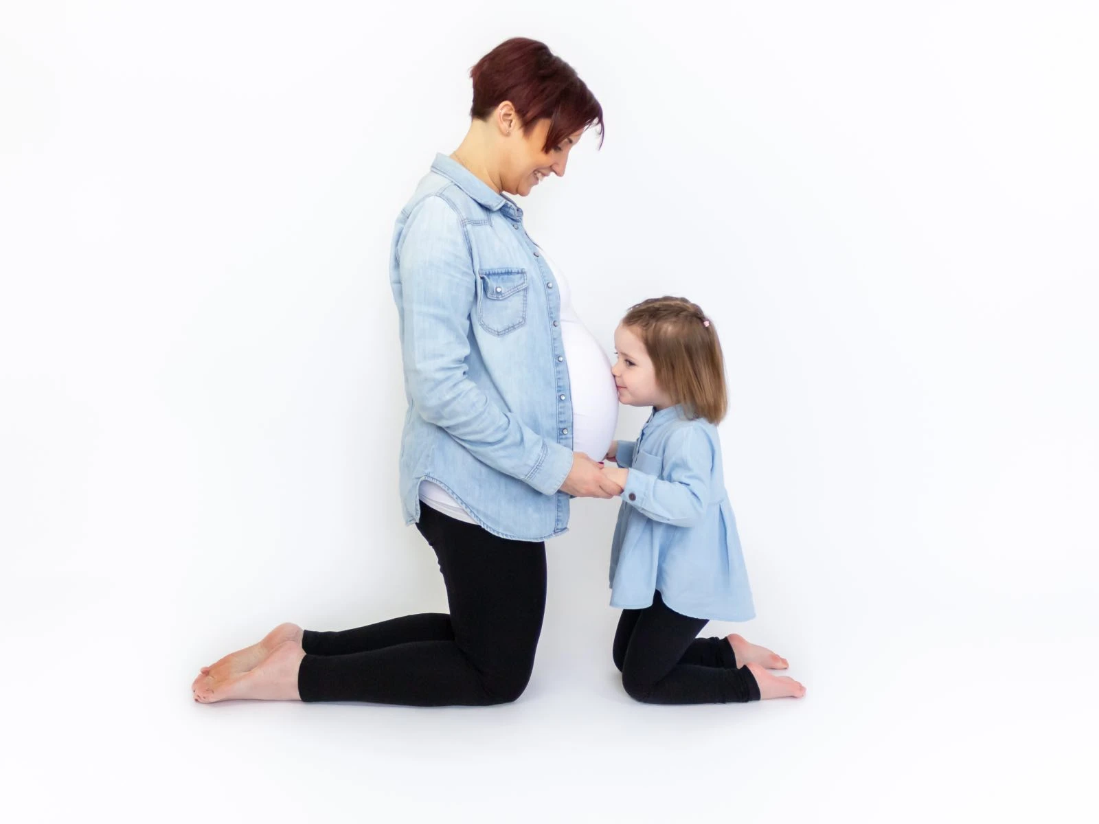 3 year old kissing her mums pregnant belly