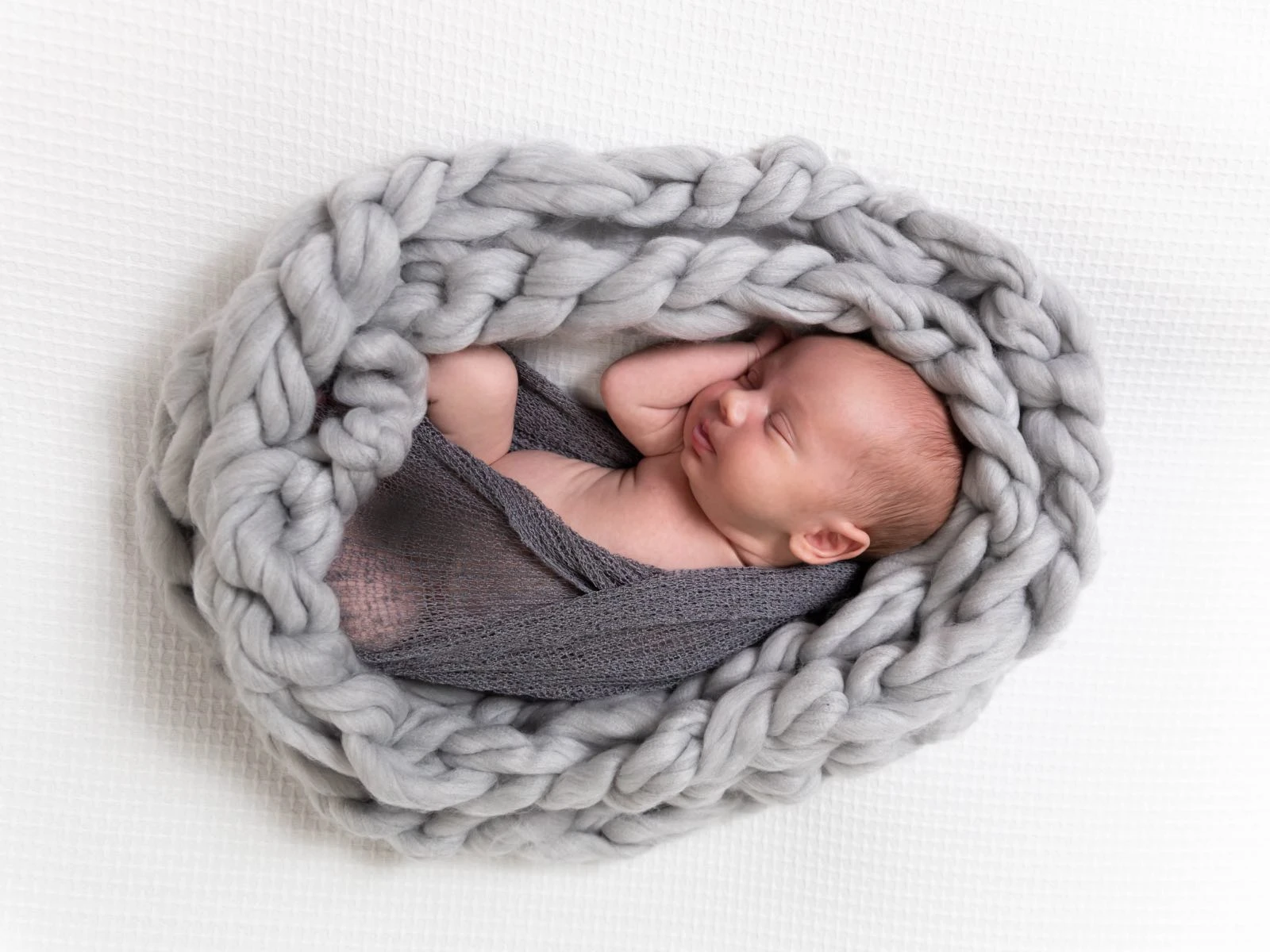 Newborn baby wrapped up in nest egg