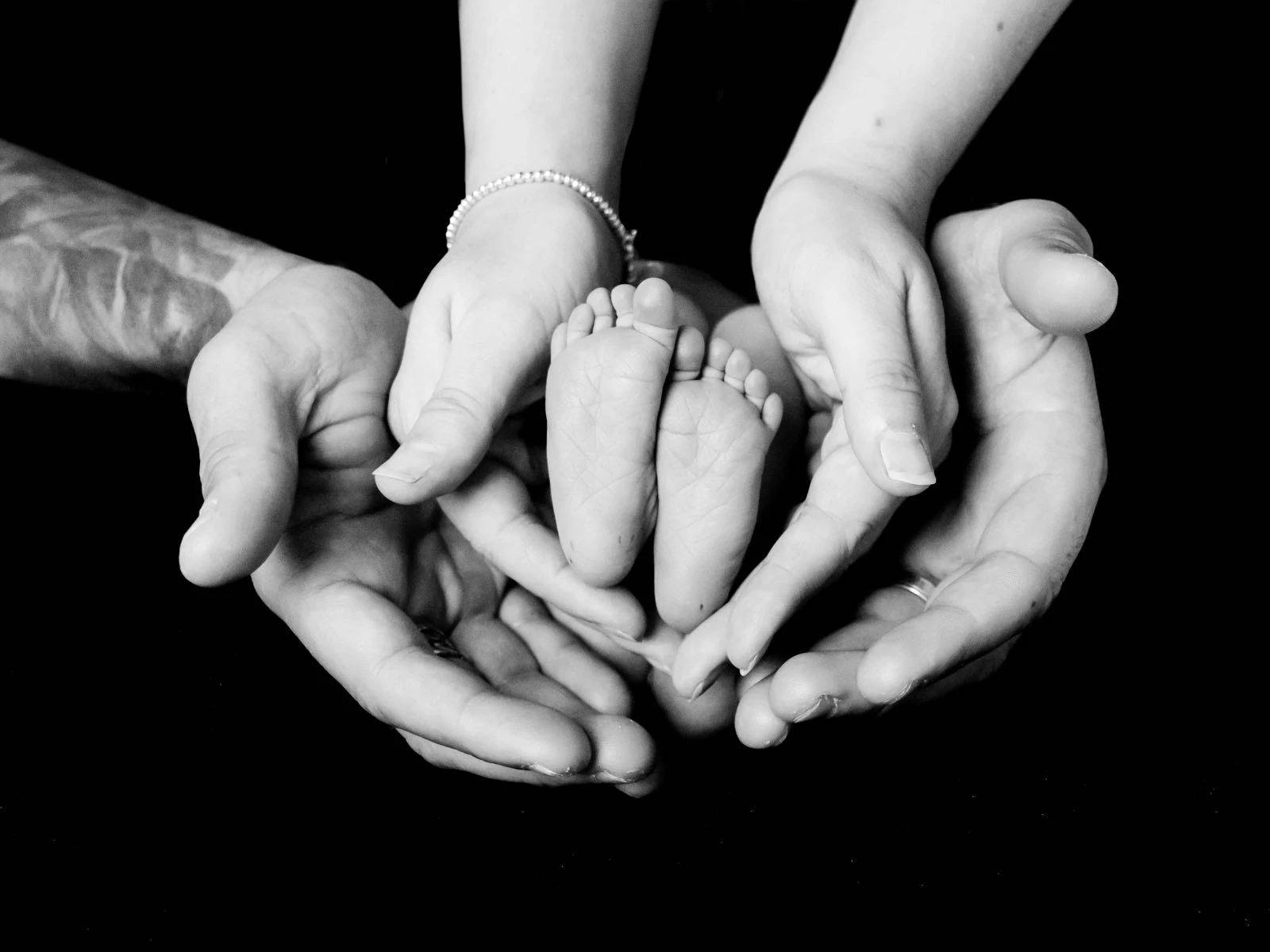 Parents hands holding newborn baby's feet