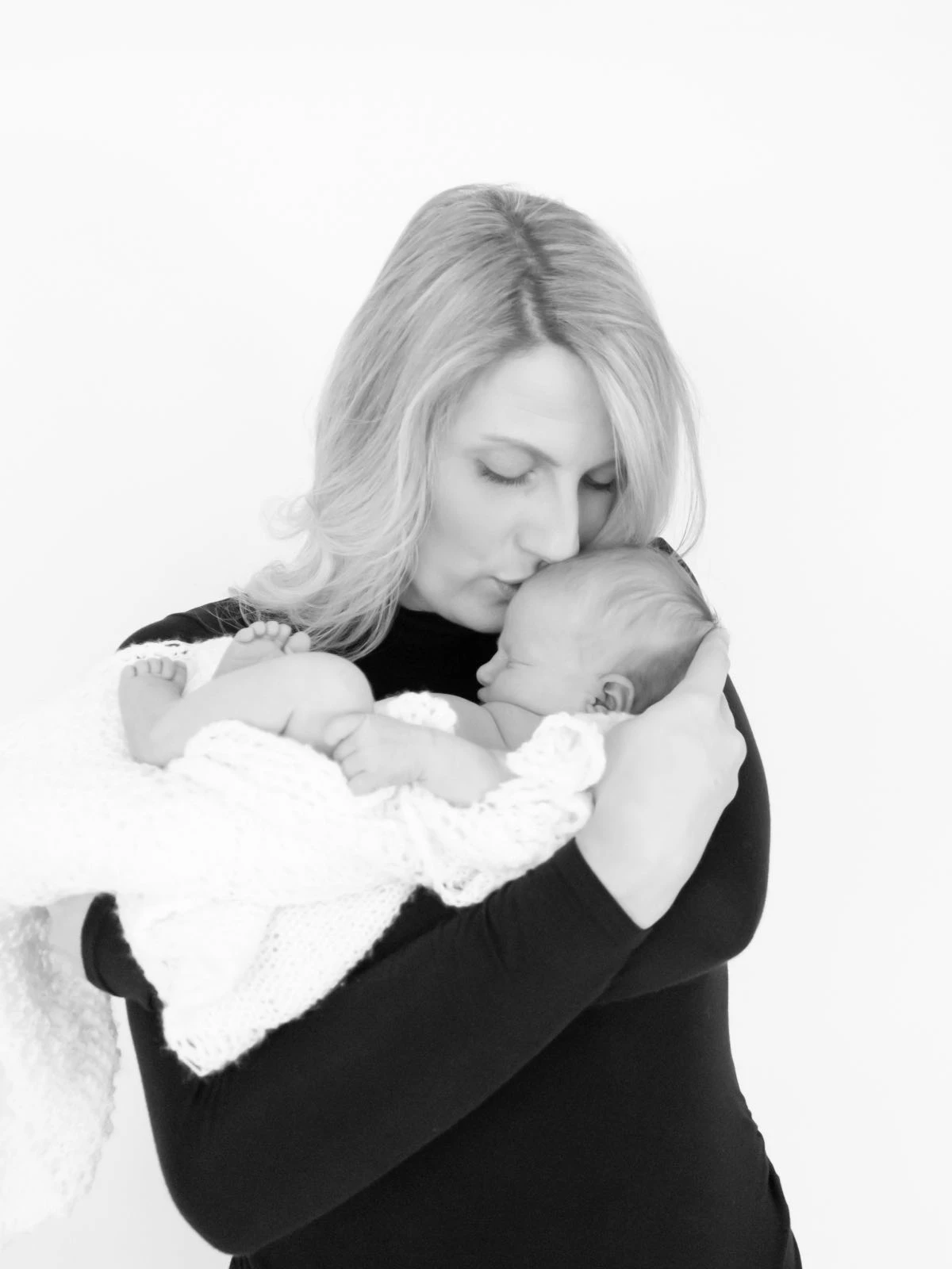 Mum holding and kissing her newborn baby